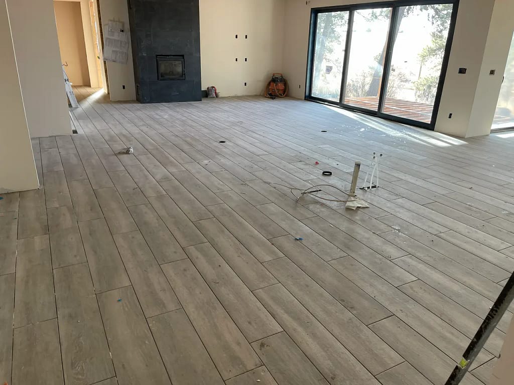 Finished wood-look living room tile flooring installed by XCEL TILE near large sliding glass doors in a residential home in Parker, Colorado.