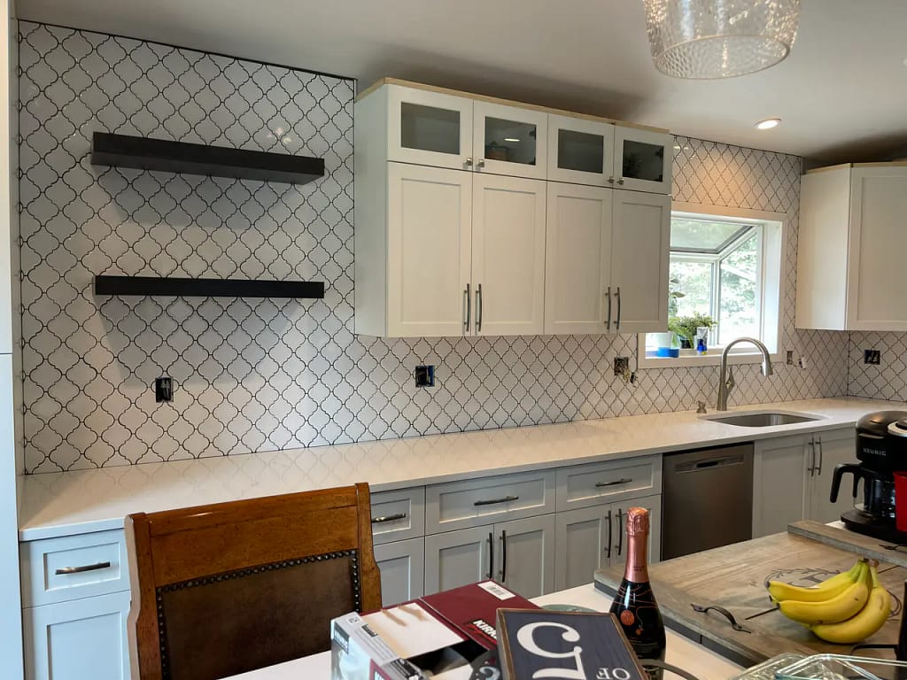 Wide view of a modern kitchen remodel showing a completed white arabesque tile backsplash extending to the ceiling behind dark floating shelves. XCEL TILE - Custom Tile Services Colorado Springs