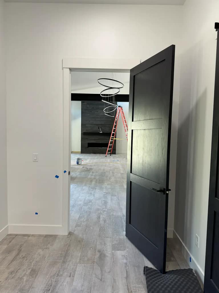 View through a black interior doorway showing seamless wood-look tile flooring transitions between rooms.