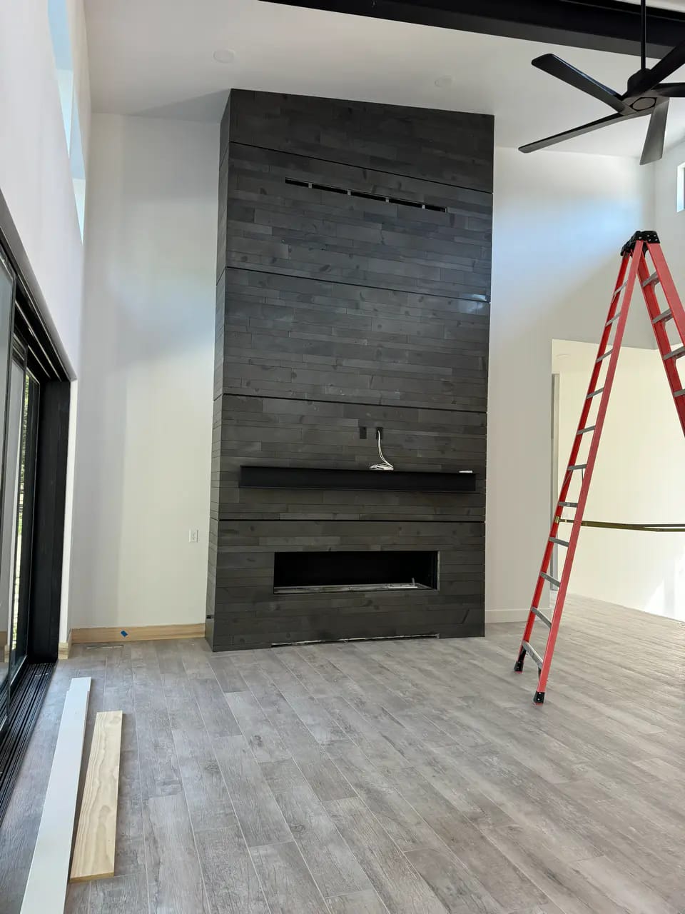 Modern living room featuring a tall floor-to-ceiling fireplace surround tiled with dark stacked horizontal porcelain planks.